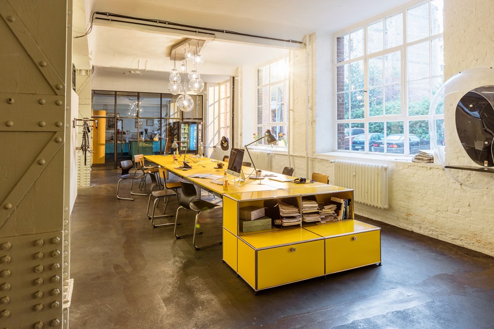 Estación de trabajo compartida amarilla USM Haller en una oficina moderna de plano abierto