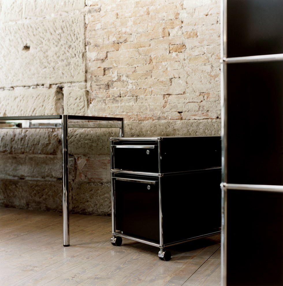 caisson avec tiroirs USM Haller chrome et noir dans une salle de bain en briques apparentes