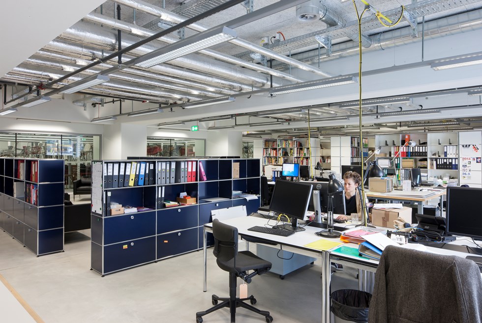 Ufficio open space in stile industrial con schedari USM Haller e postazioni di lavoro
